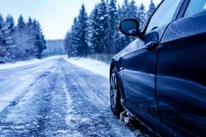 Car driving through snowy road in Calgary during winter, highlighting the importance of seasonal tire changes for safe driving.